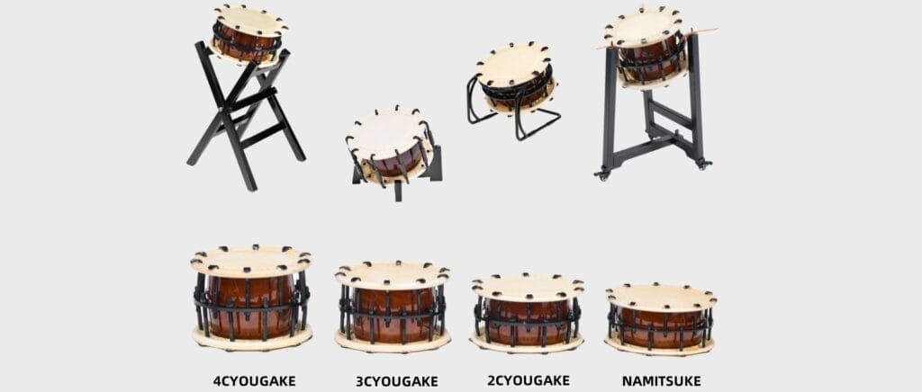 A collection of Japanese Shime-daiko (rope-tuned Taiko drums) showing different sizes—4 Chou-gake, 3 Chou-gake, 2 Chou-gake, and Namitsuke—alongside various black metal and wooden playing stands, isolated on a light gray background.