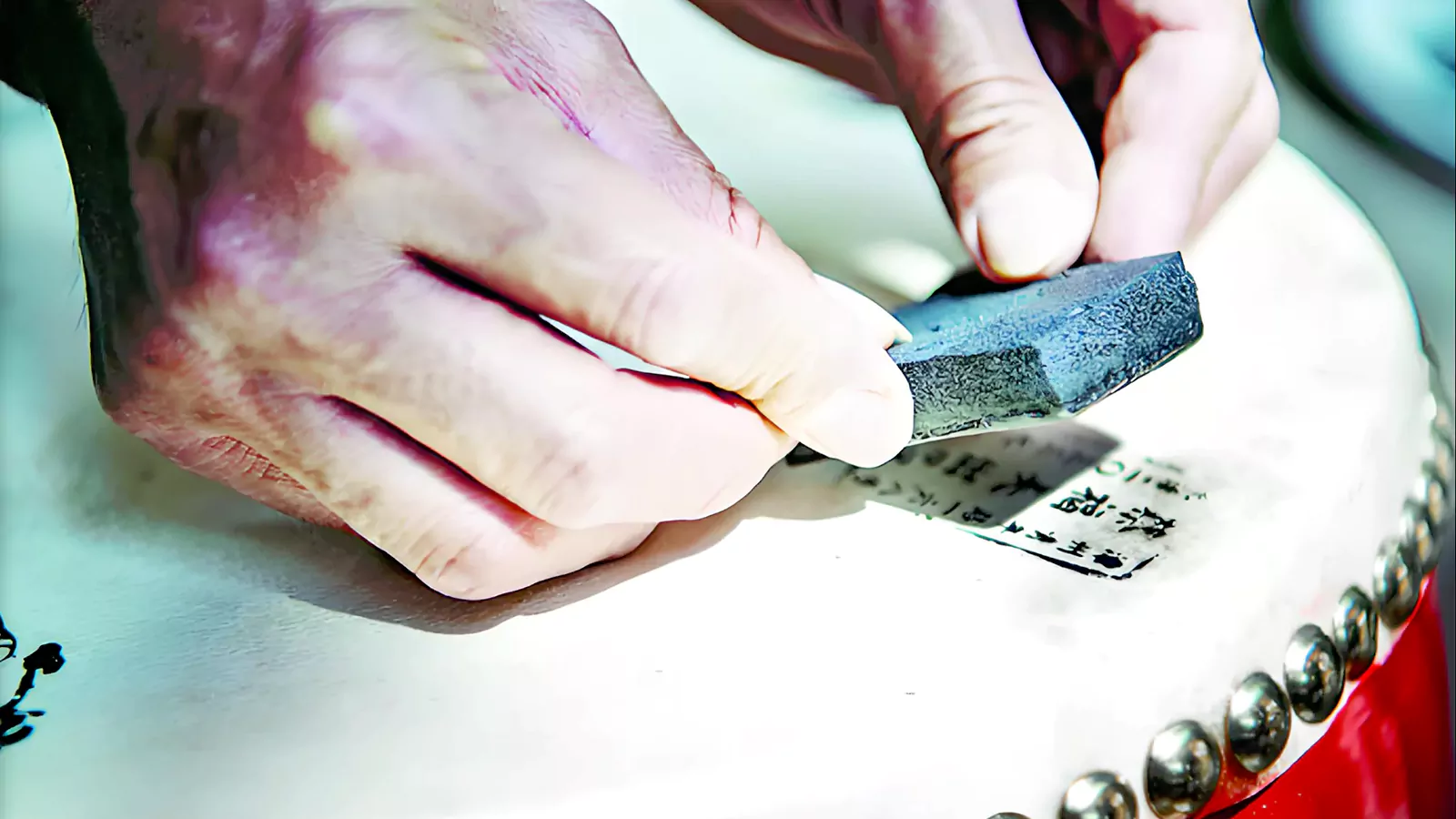 Close-up of artisan hands working on a handmade Taiko drum head, illustrating the feasibility of DIY Taiko construction.