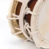 Close-up of JINLEI 3Cyougake Shime Daiko rope drum showing double-row stitched leather drumhead rim, thick white twisted rope tension lacing with multiple knotted ties against amber lacquered wood shell