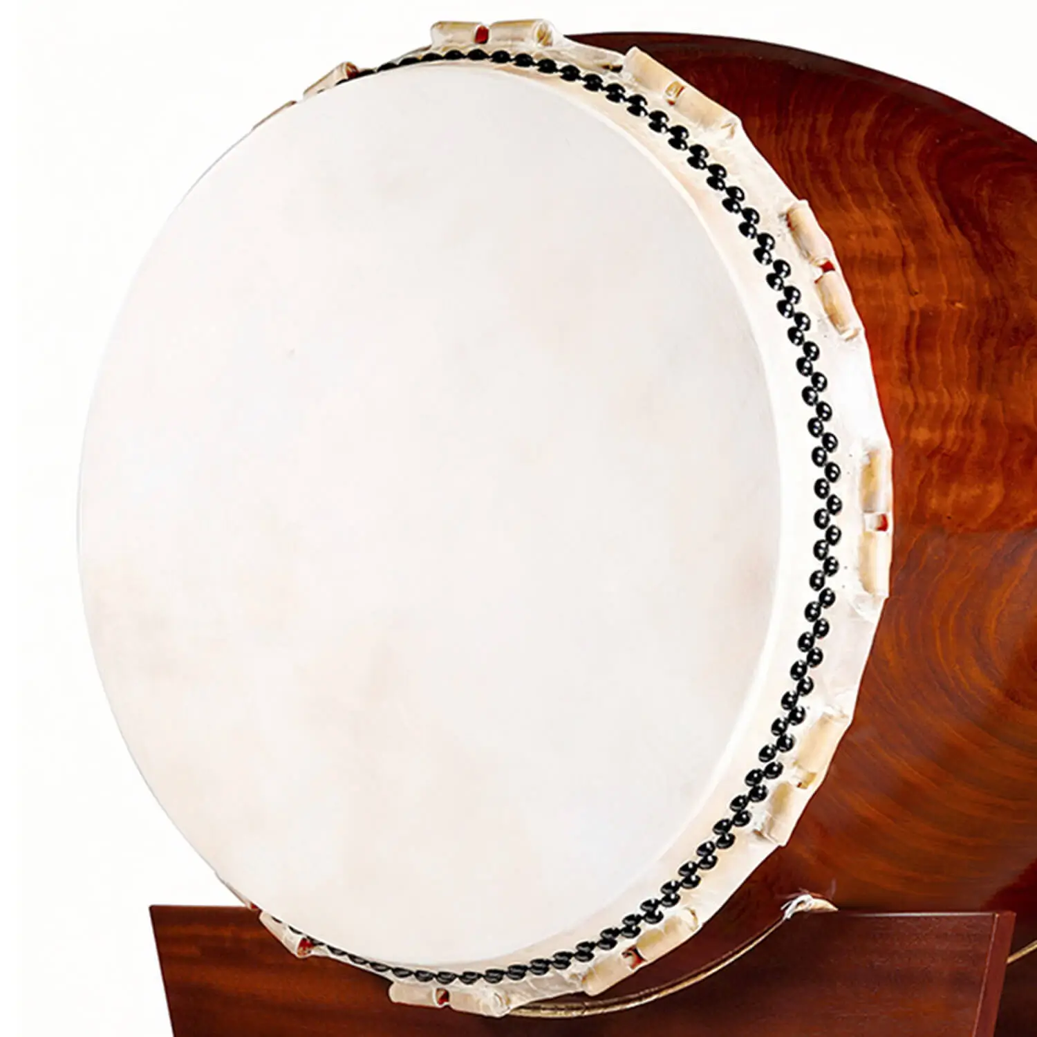 Close-up of JINLEI O-Daiko Akatsuki Series large cowhide drumhead with black bead tacking and rawhide lacing against deep reddish-brown swirling wood grain shell