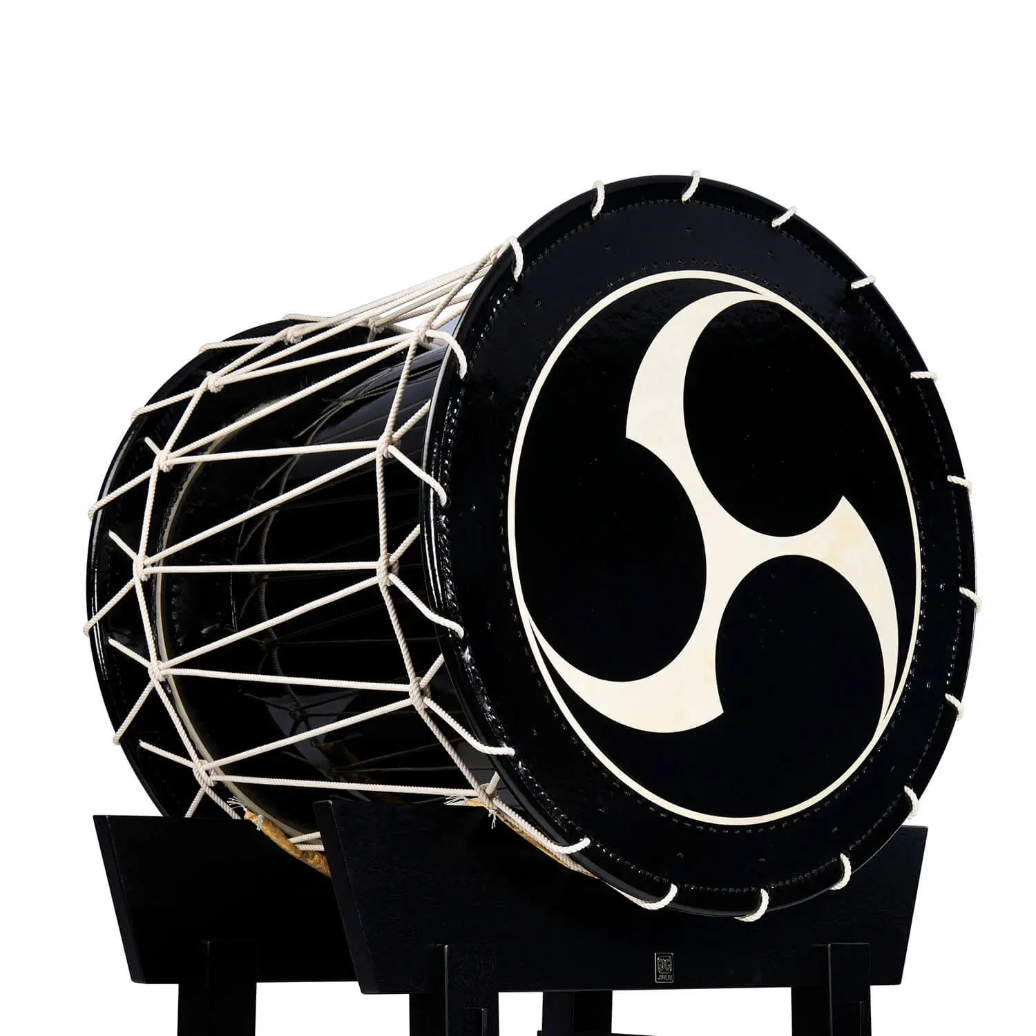 JINLEI O-Shime daiko, glossy black shell with white rope tuning and tomoe pattern drumhead on black stand, side angle view