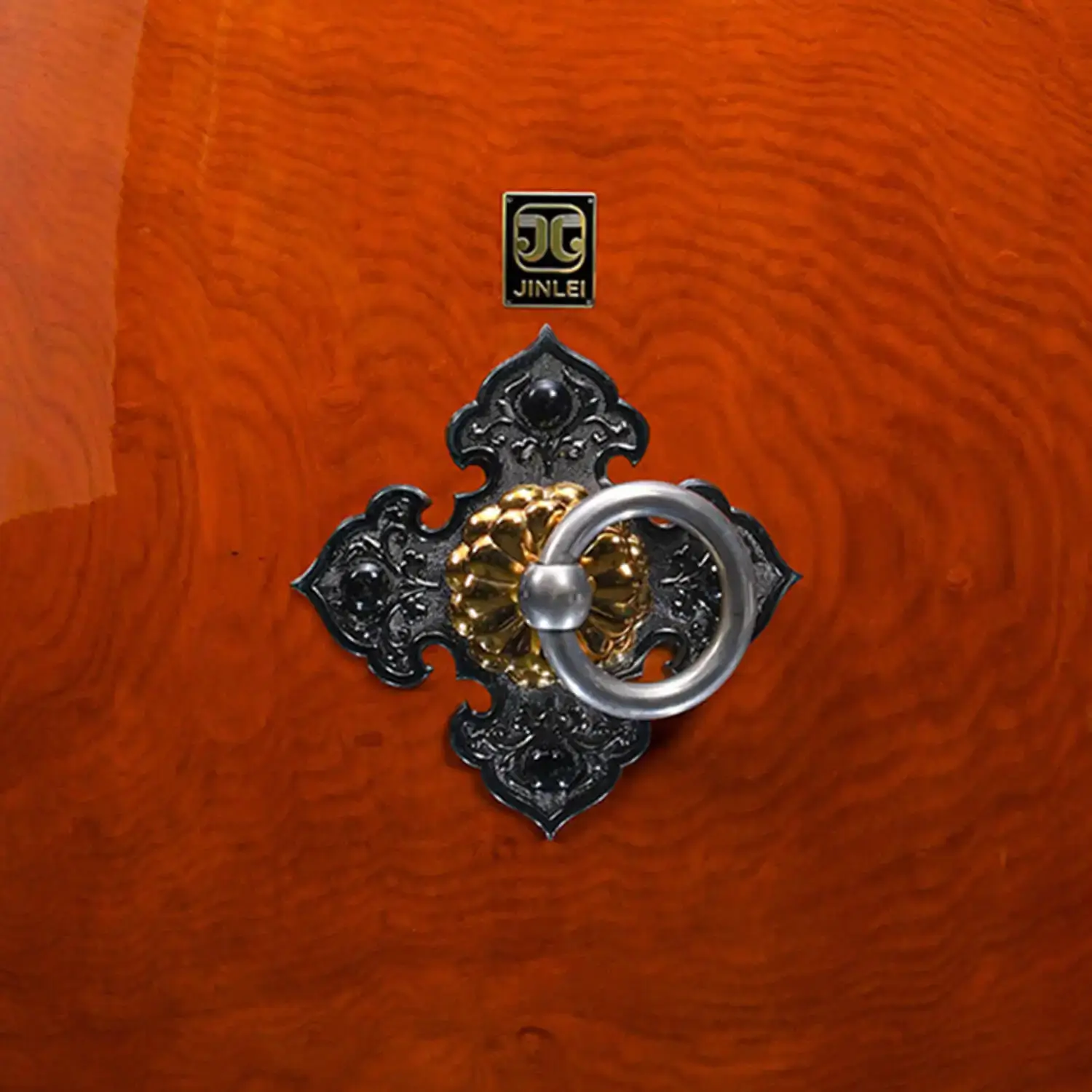 Close-up of Nagado Daiko Ash Wood drum decorative hardware featuring gold and silver ring pull on black cast iron diamond-shaped mount against high-gloss ash wood grain surface