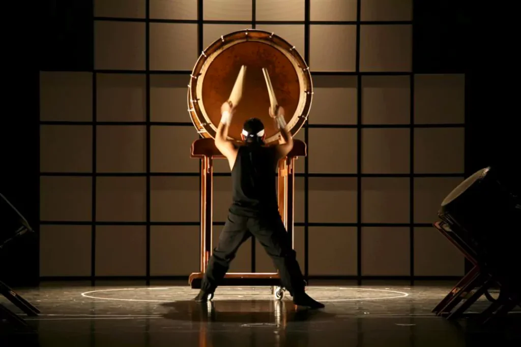 A professional performer playing a large handmade Odaiko drum on stage, demonstrating the powerful resonance achieved through careful DIY construction.